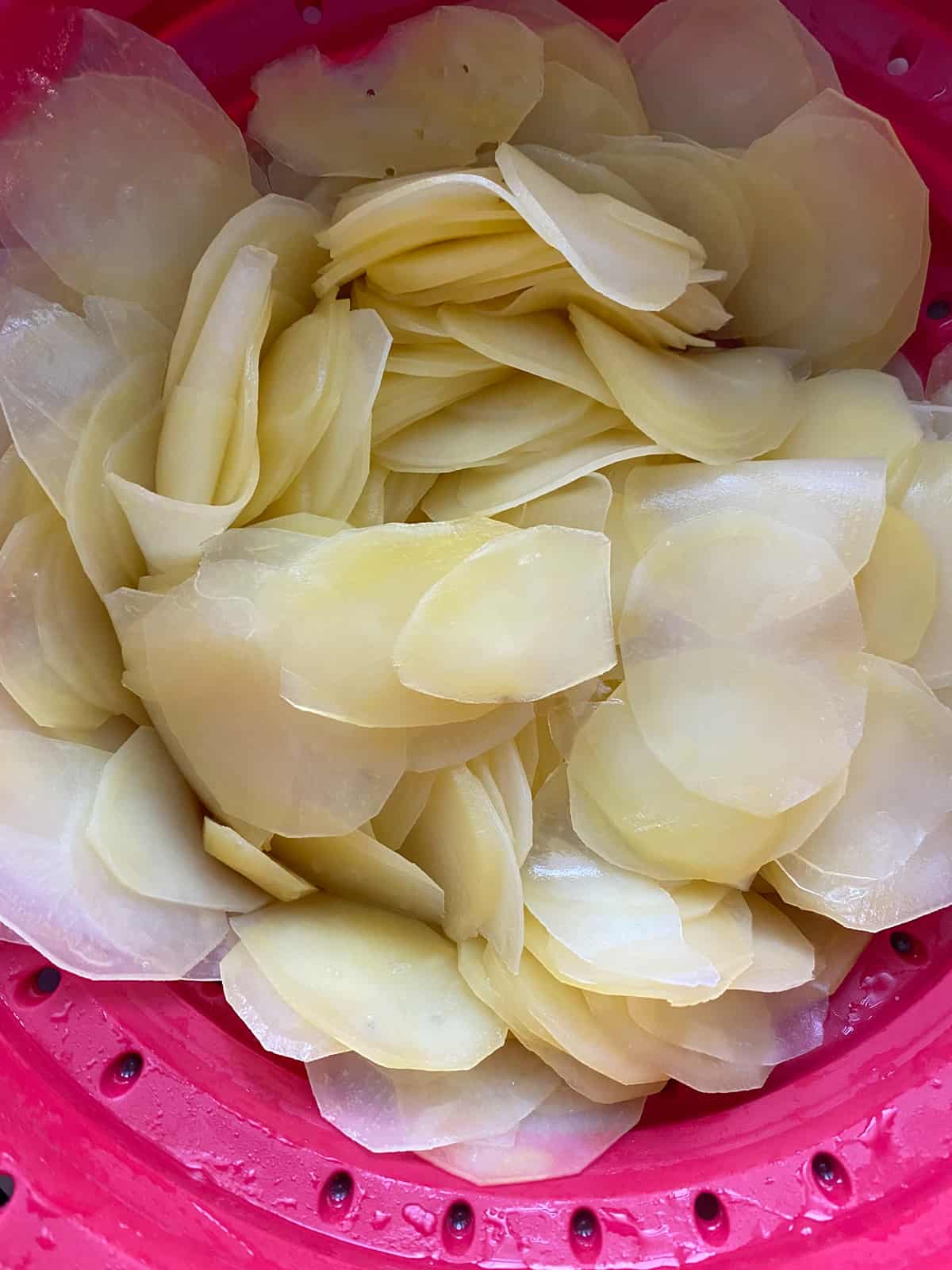 Microwaved sliced potatoes, drained, in a colander.