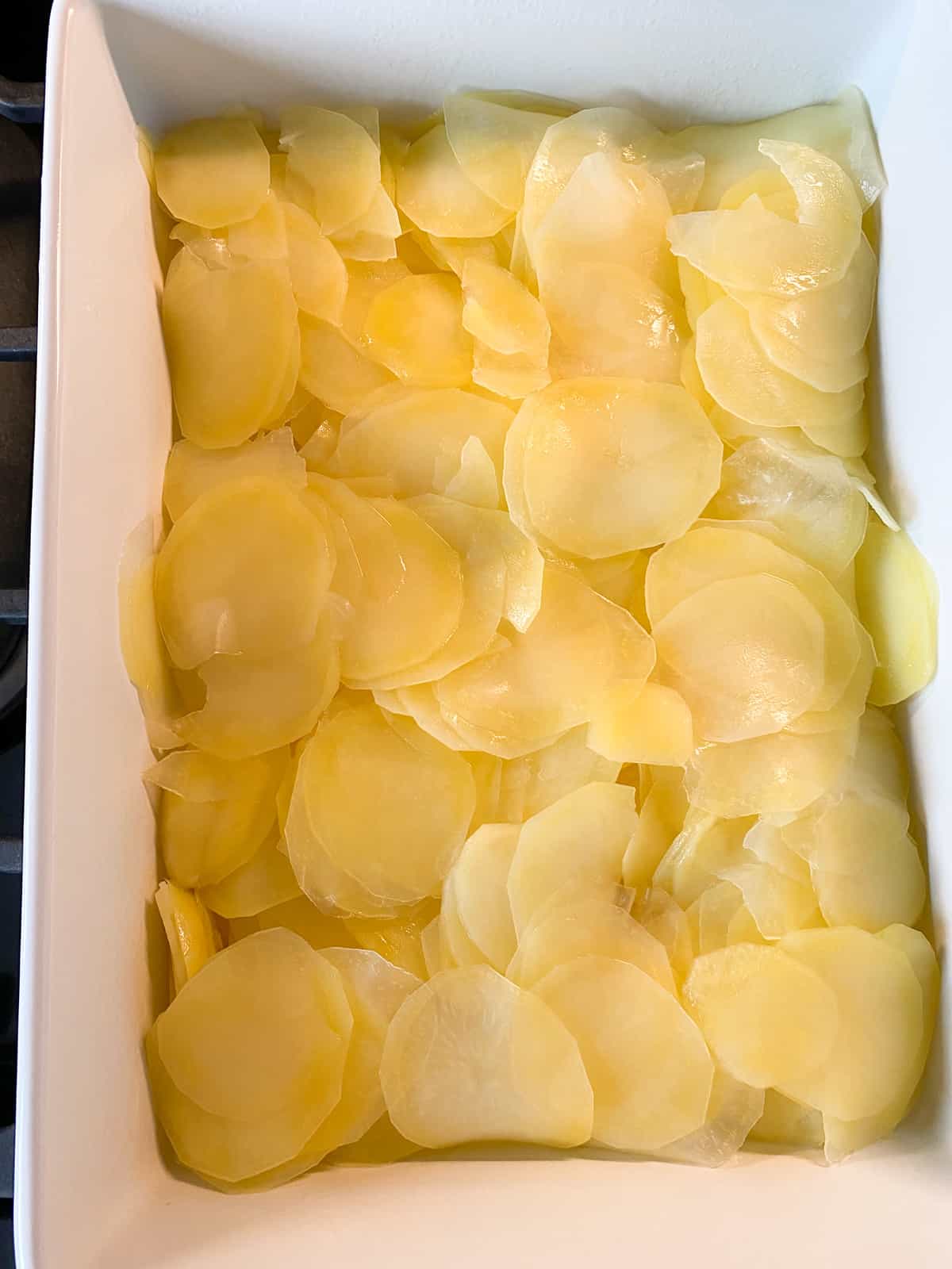 Pre-cooked, sliced potatoes in a baking dish.
