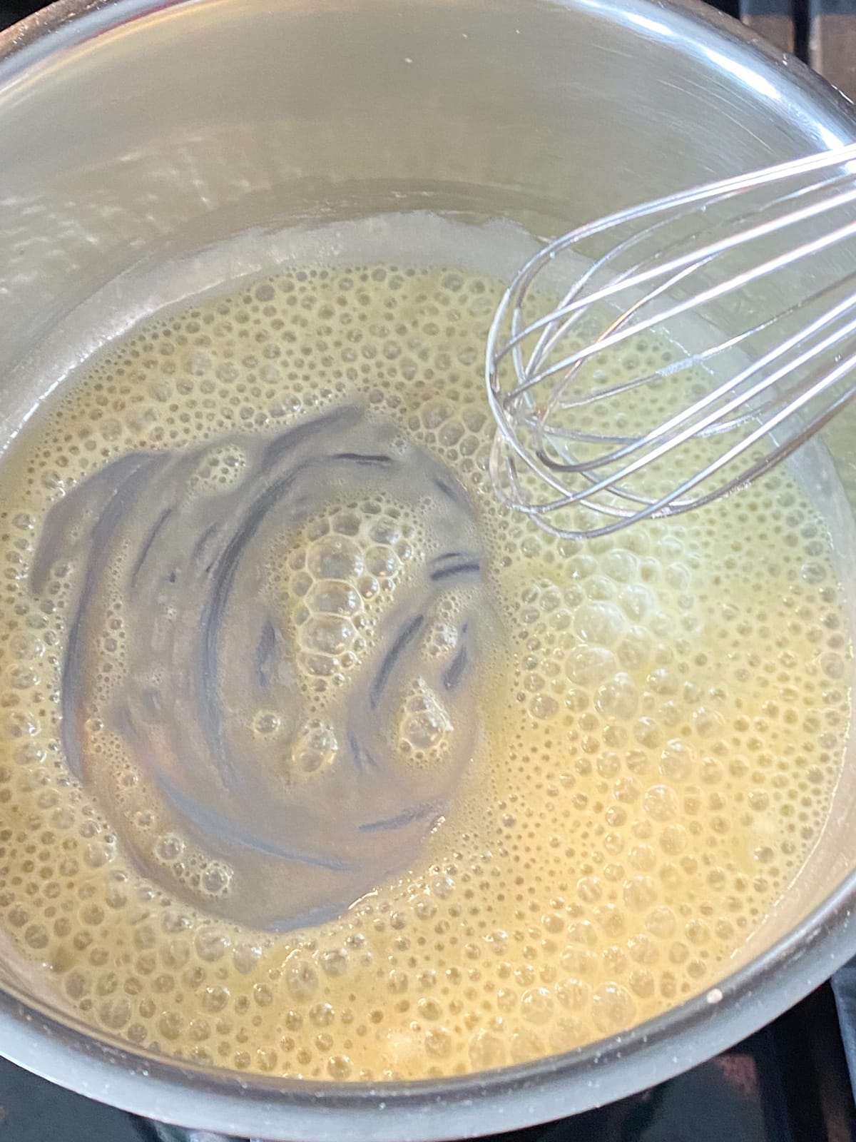 Oil and flour being whisked together in a pot.