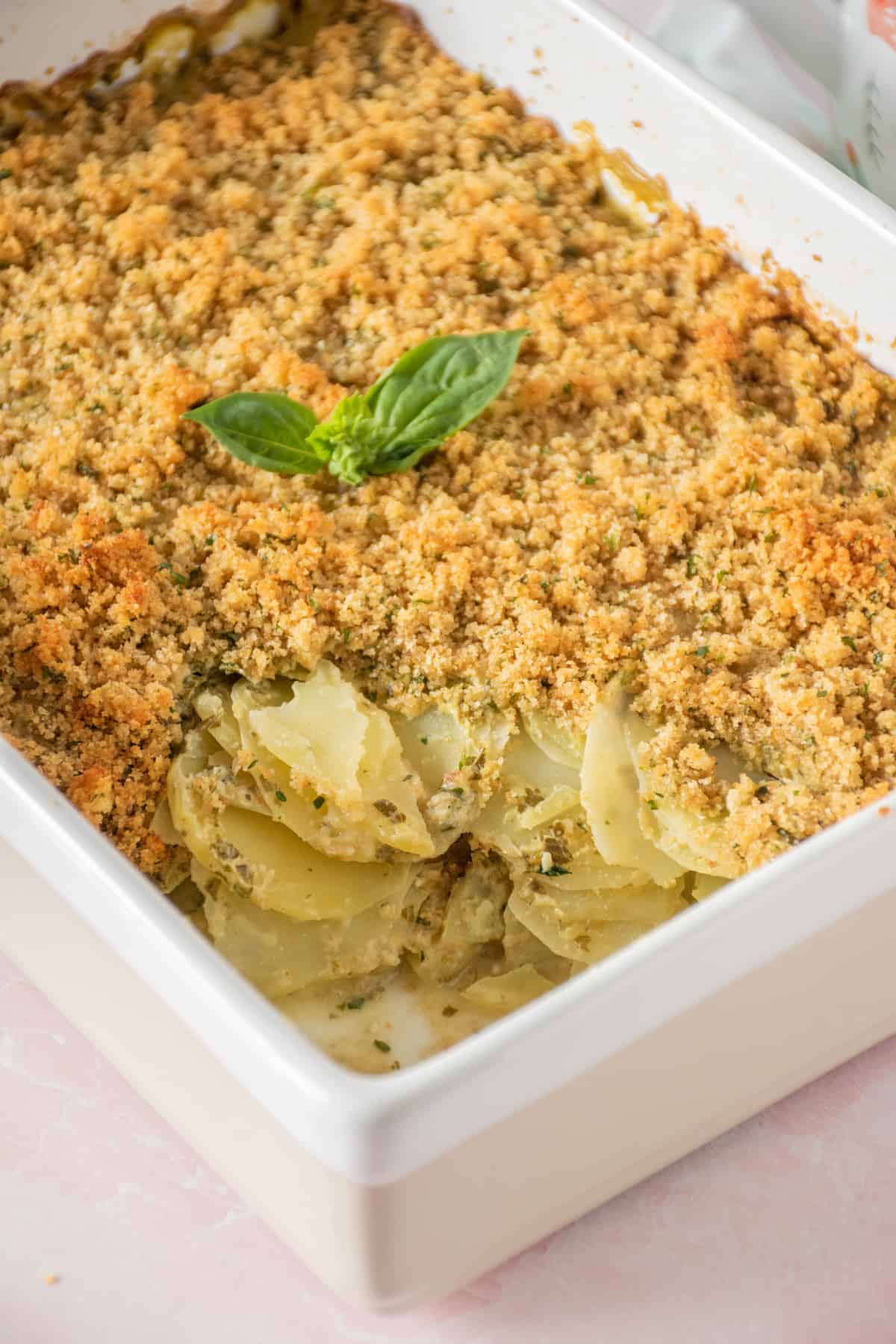Baking dish of herb scalloped potatoes with a spoonful removed to see layers.