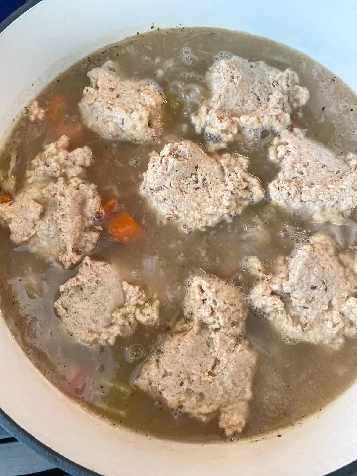 Dumpling batter dropped into simmering stew by the spoonful.