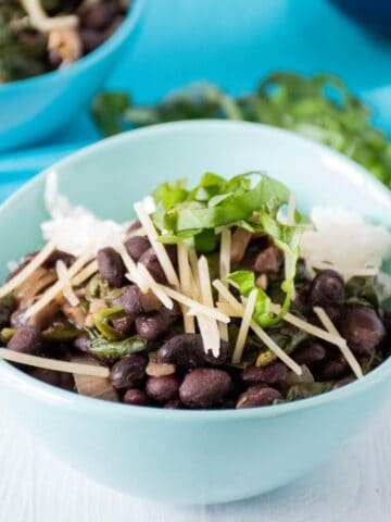 Bowl of black beans and rice, garnished with fresh basil and shredded parmesan cheese.