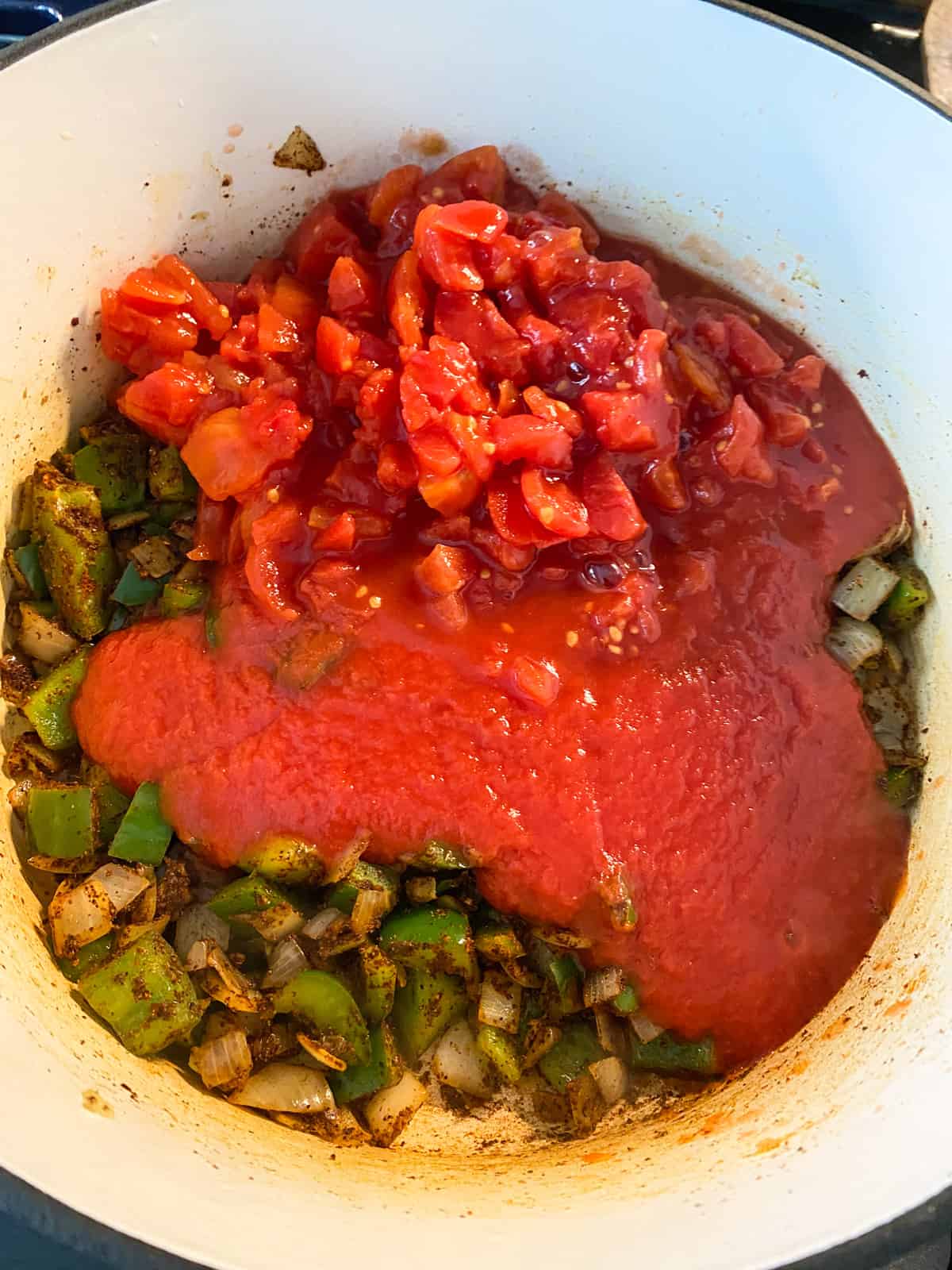 Diced tomatoes and tomato sauce added to pot of sauteed vegetables.