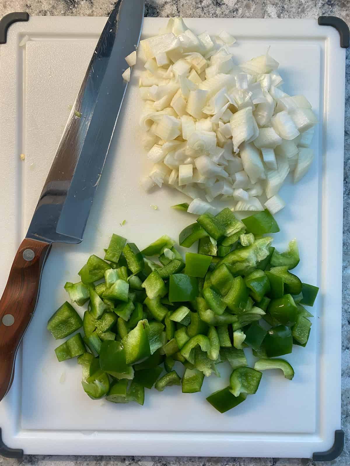 Peppers and onions, chopped, on a cutting board.