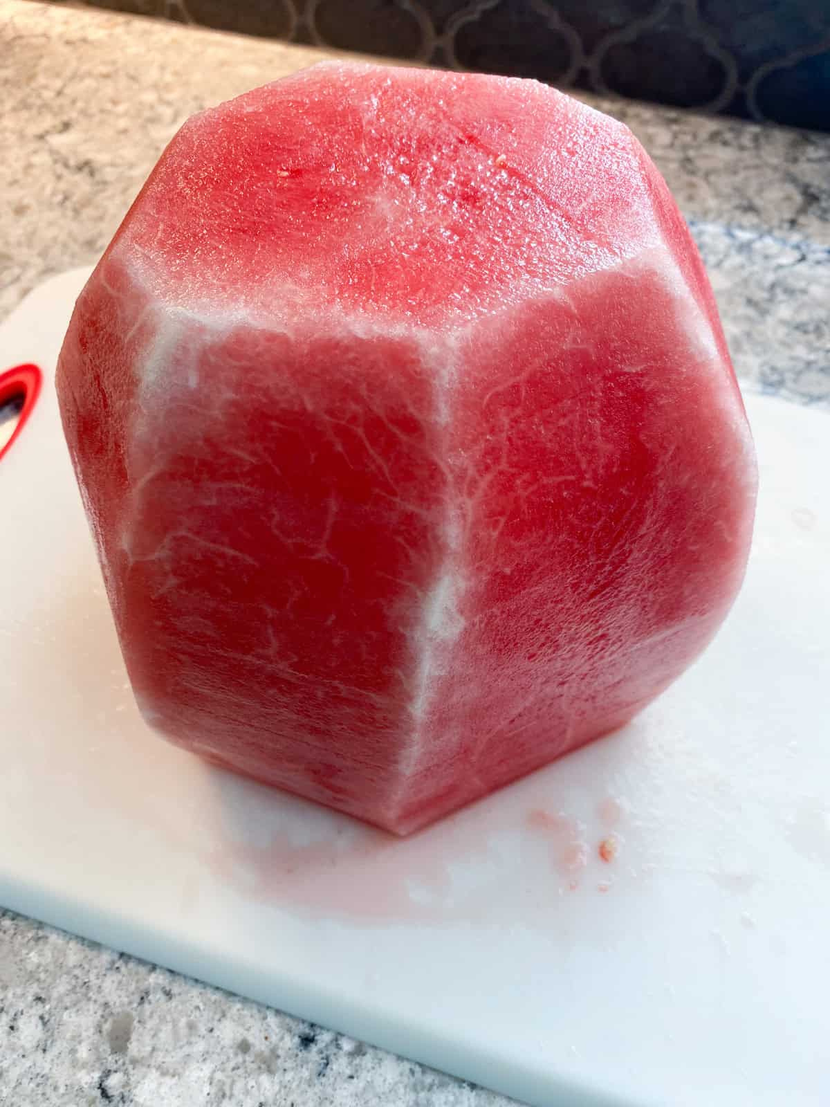 A whole watermelon with all the rind cut off, both green and white parts.