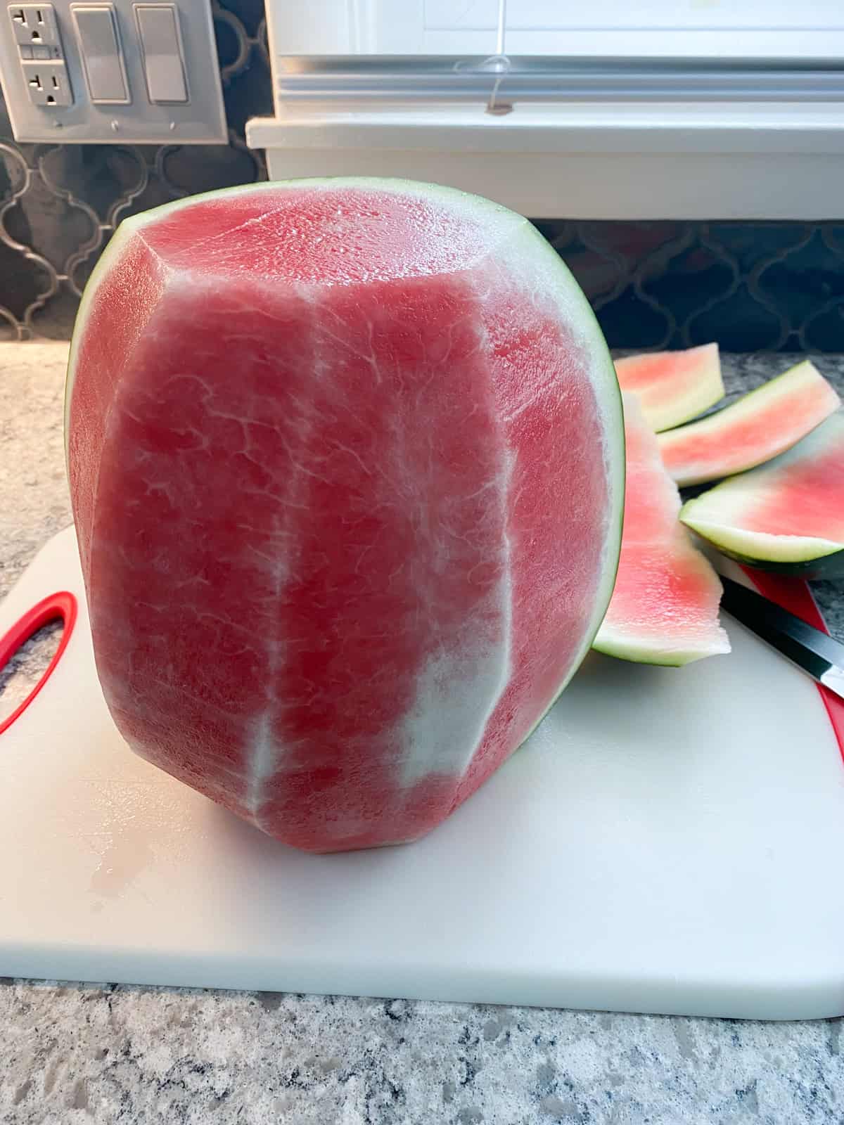 Whole watermelon with the green and white parts of the rind partially cut off.
