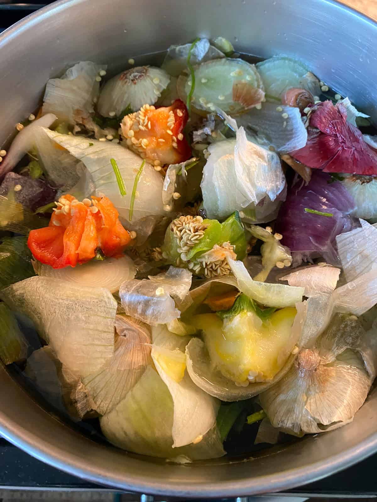 Water added to frozen vegetable scraps in a stock pot.