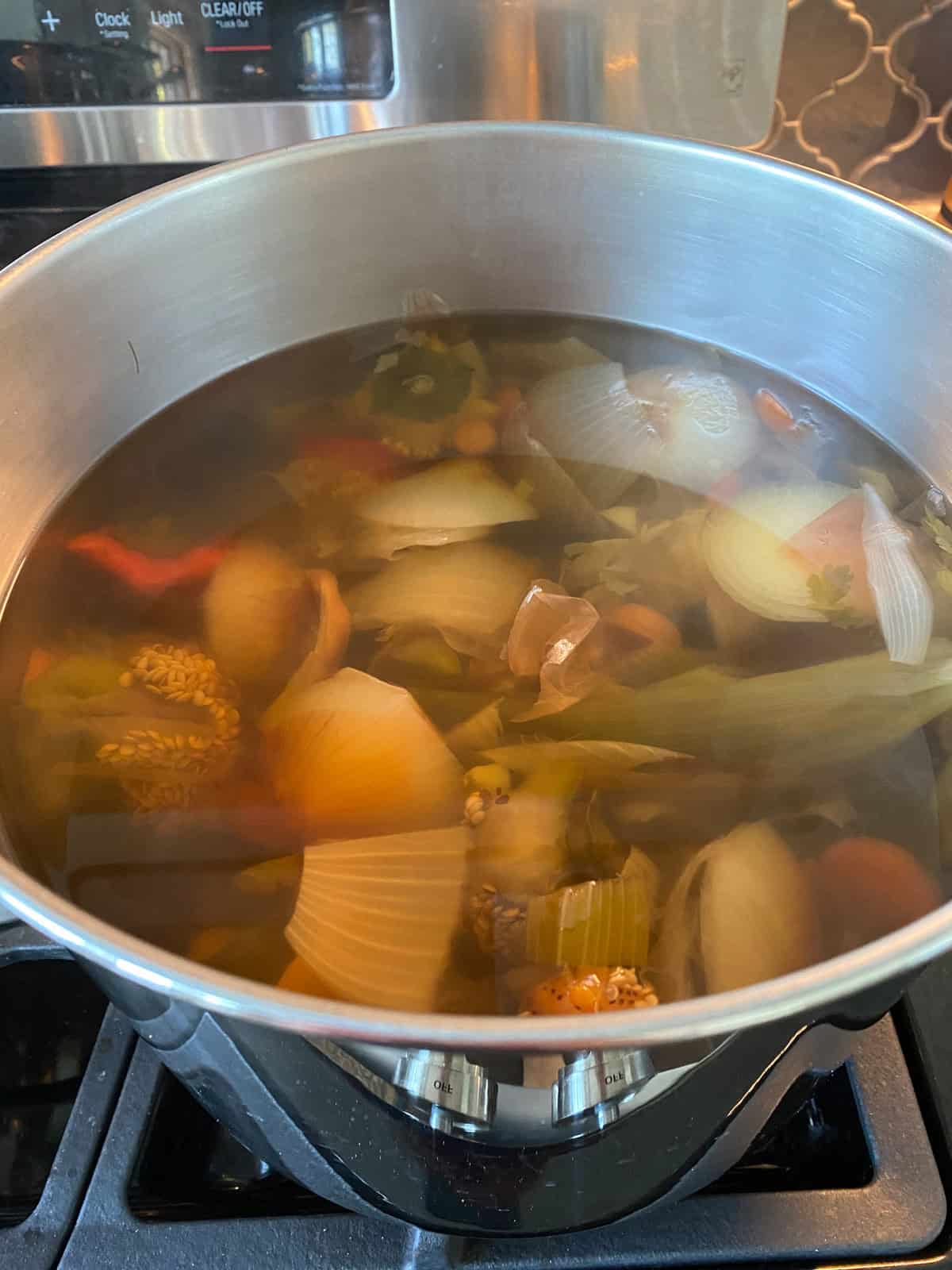 Vegetable stock with scraps still in, ready to strain.