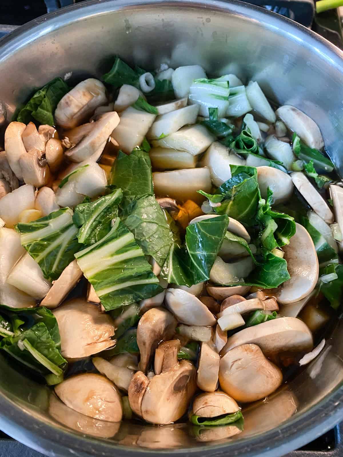 Bok choy and mushrooms added to the simmering vegetable broth.