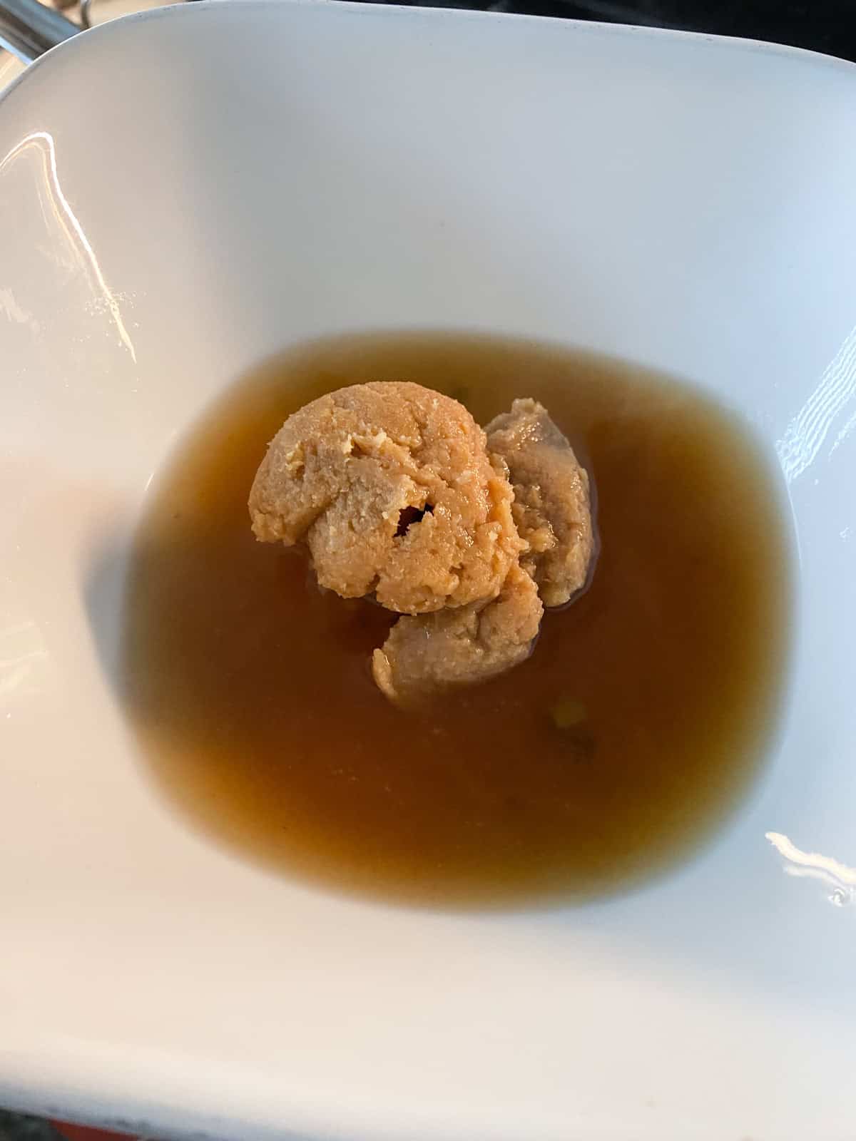 Miso paste and a little vegetable broth in a bowl.