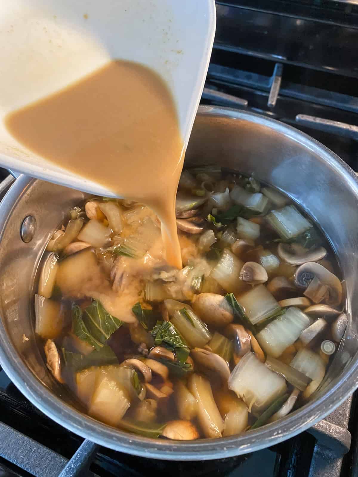 Miso/vegetable broth mixture being poured into the soup.