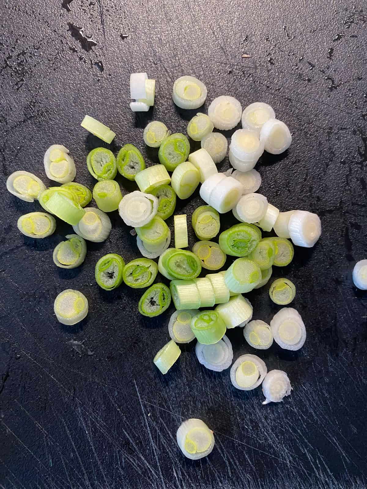 Sliced green onions - the white part only - on a cutting board.
