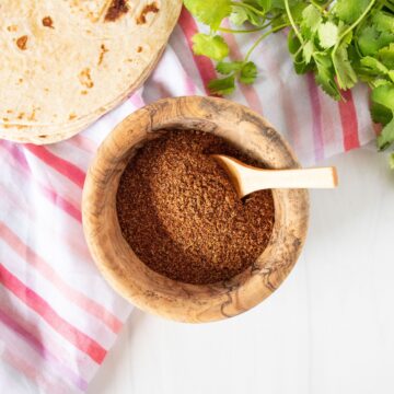 Small wooden bowl with taco seasoning in it, and a wooden spoon.