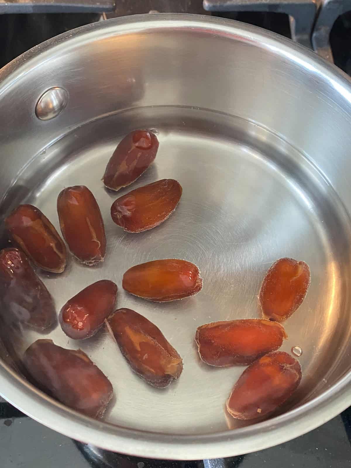 Small pot with hot water and dates in it.