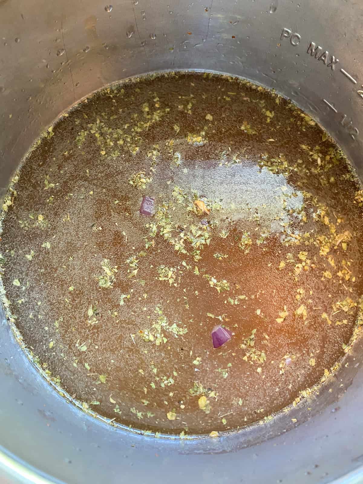 All refried beans ingredients added to the pressure cooker pot.
