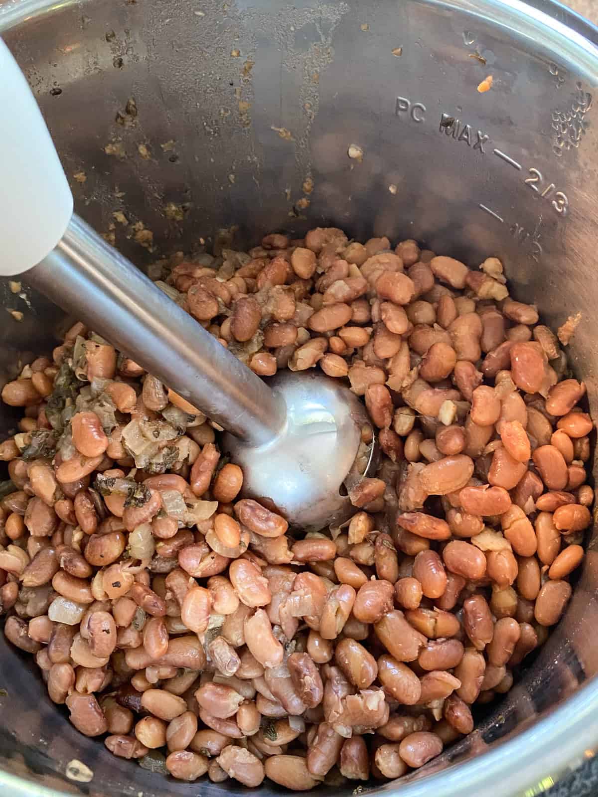 Cooked pinto beans, drained, in pressure cooker, with immersion blender.