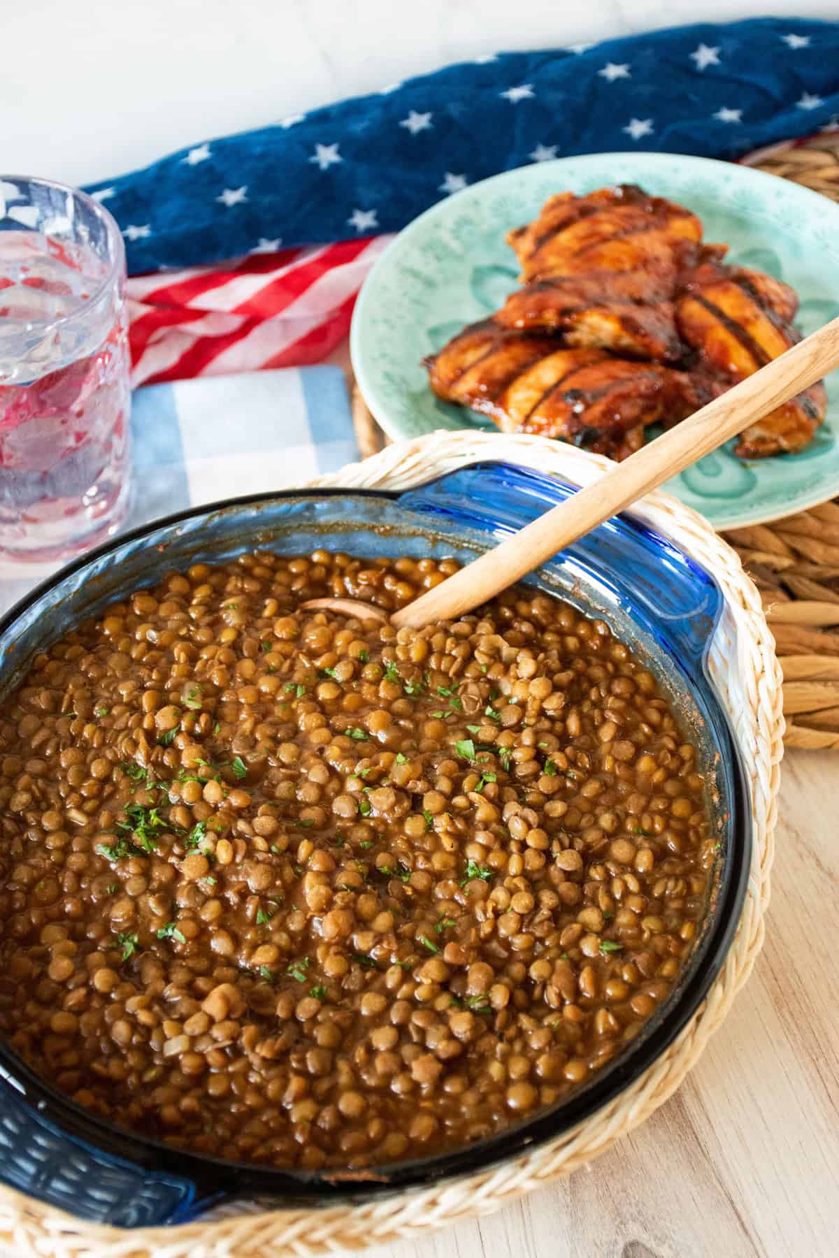 Glass baking dish with lentil baked beans and a wooden spoon in it.