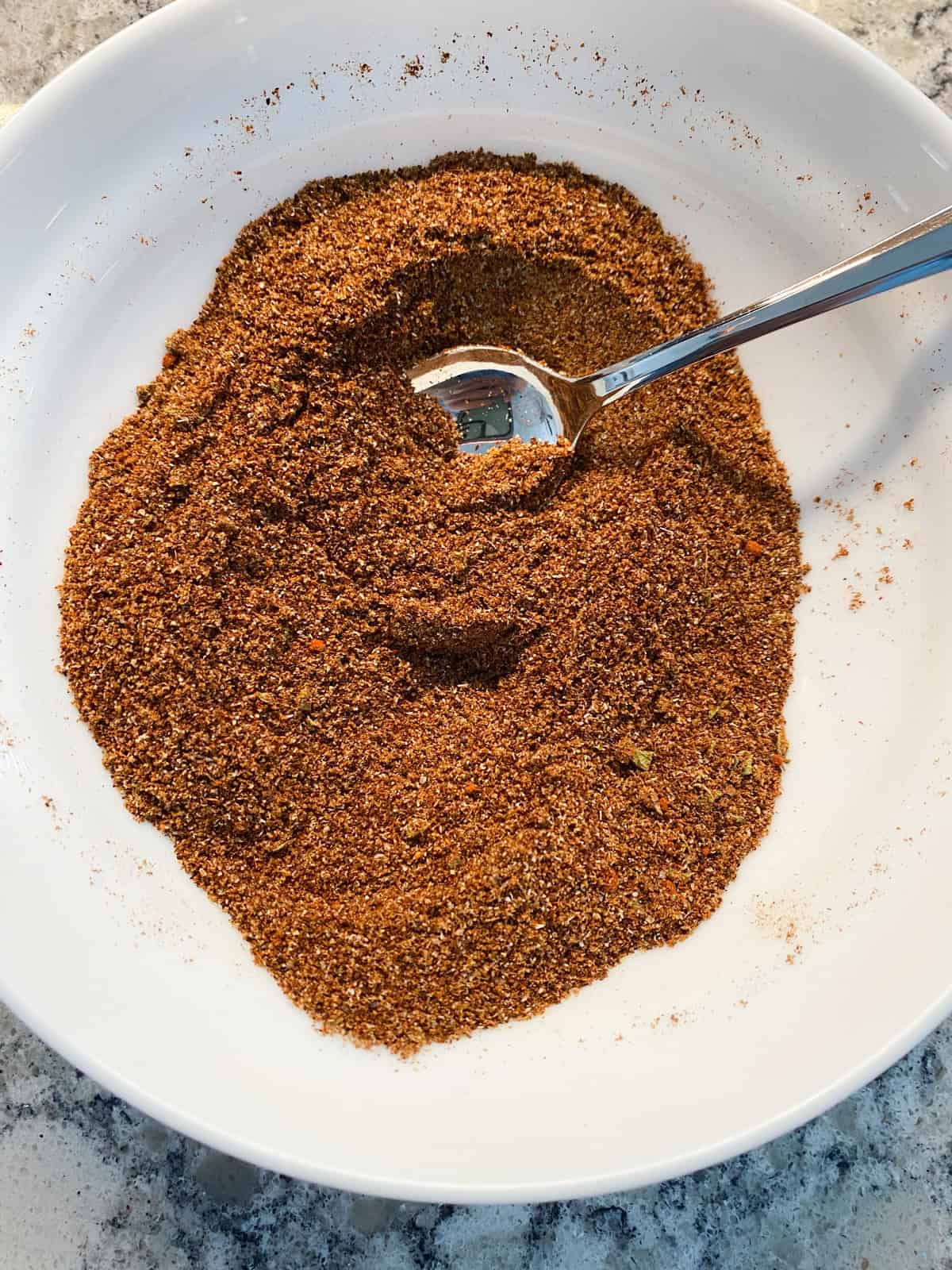 All spices combined into taco seasoning, in a white ceramic bowl.