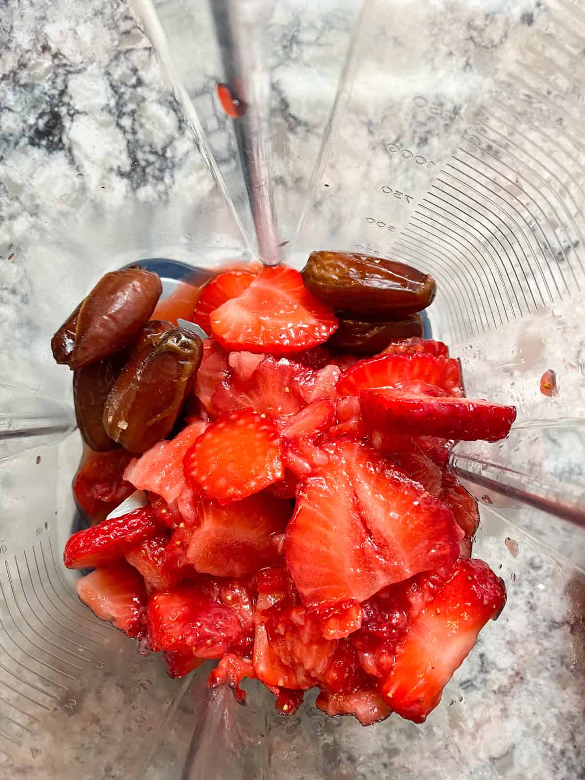 Mashed strawberries and dates in a blender.