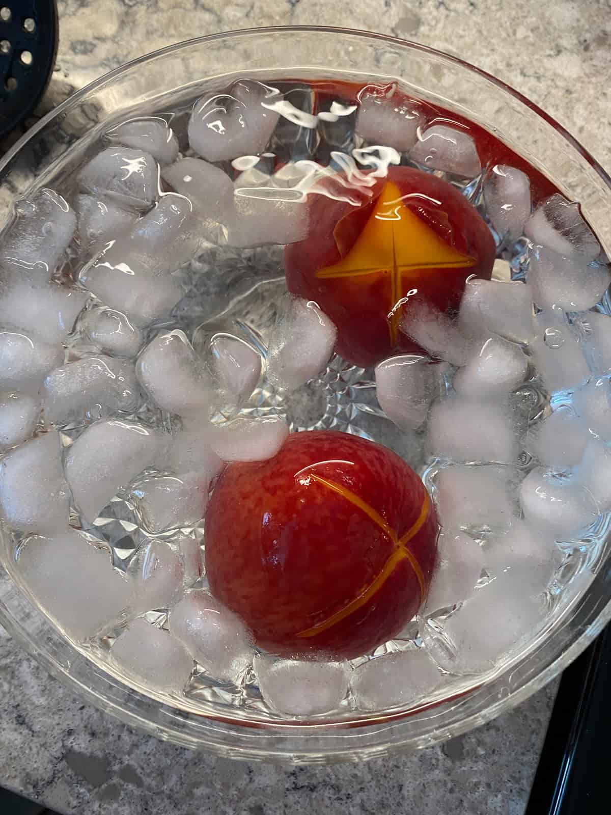 Peaches in a bowl of water and ice to shock after blanching.