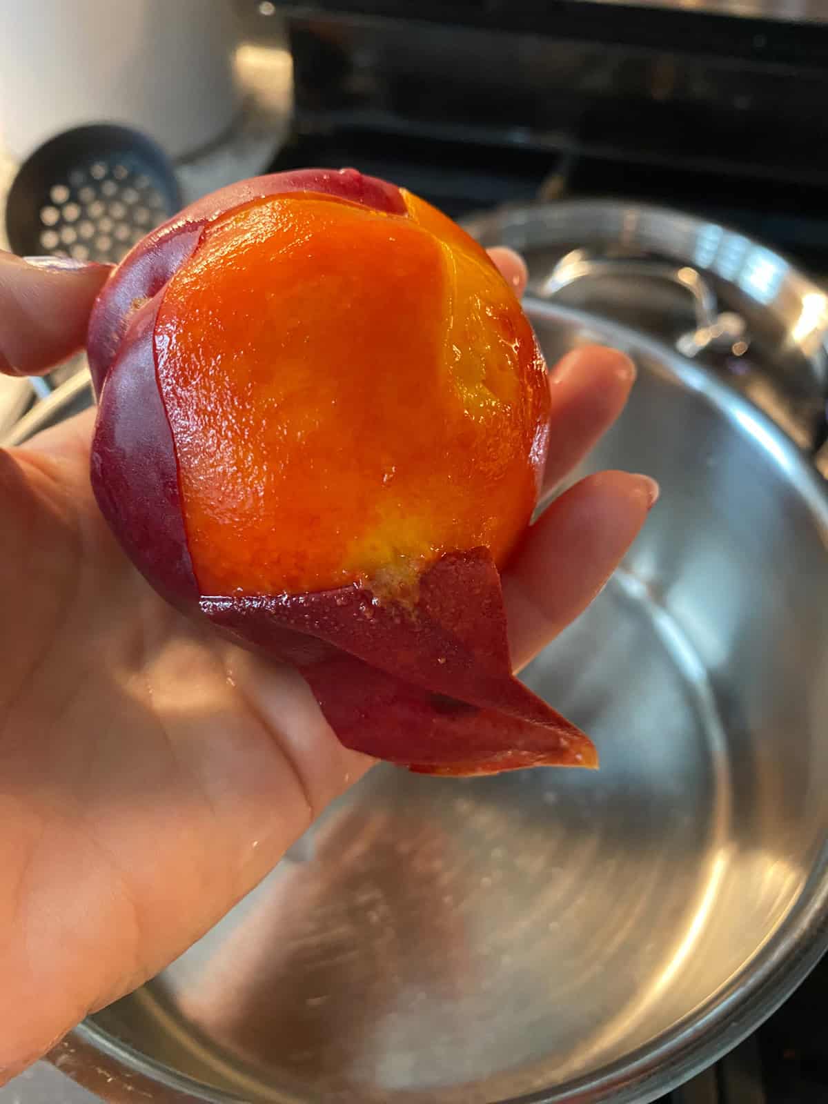 Peach being peeled after blanching.