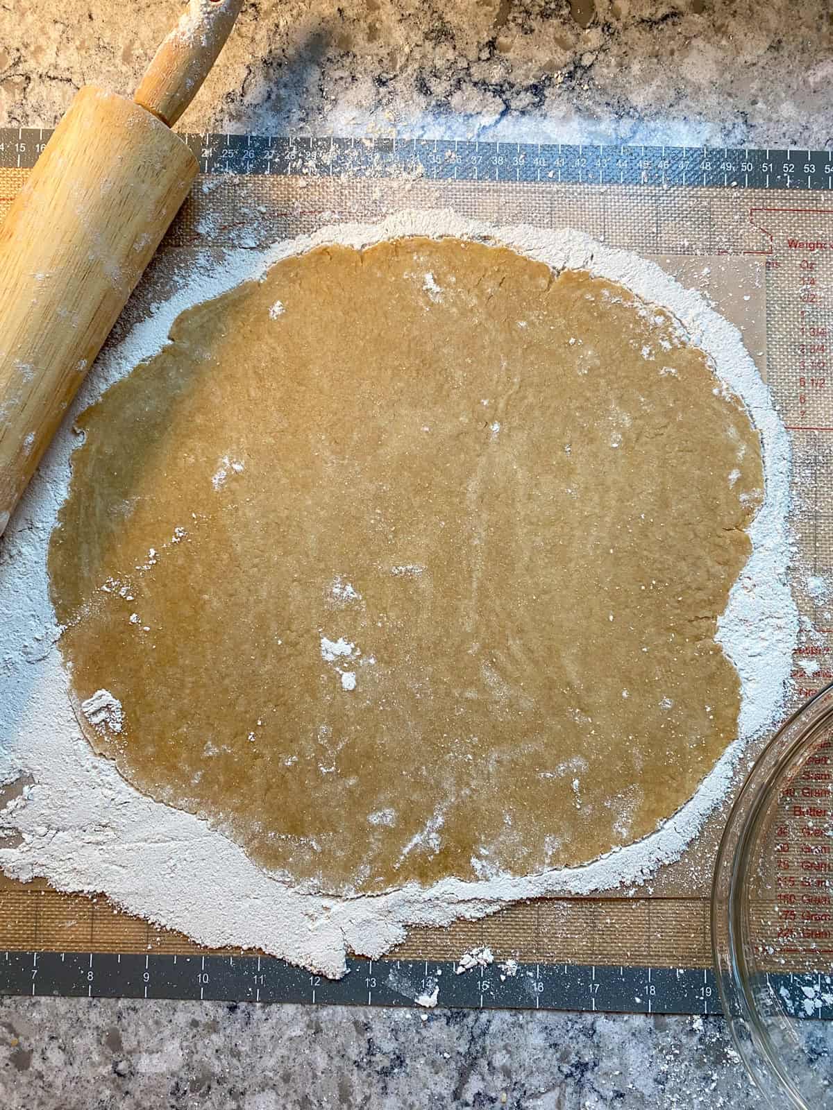 Pie crust rolled out on a silicone mat.