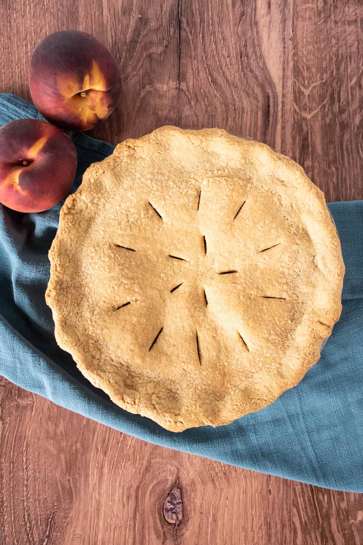 Whole pie with fresh peaches beside it.