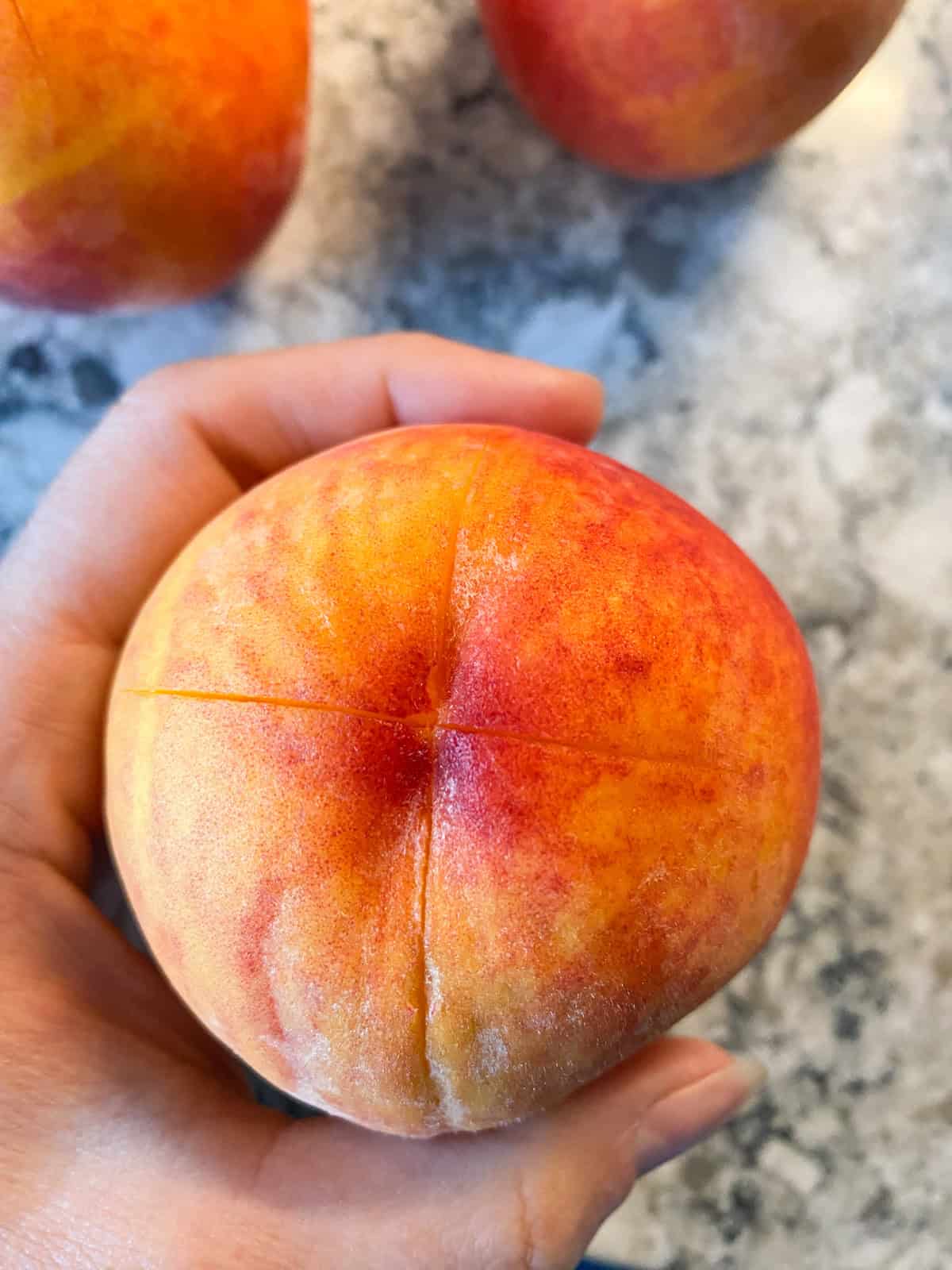 Fresh peach with an "x" shape sliced in the bottom.