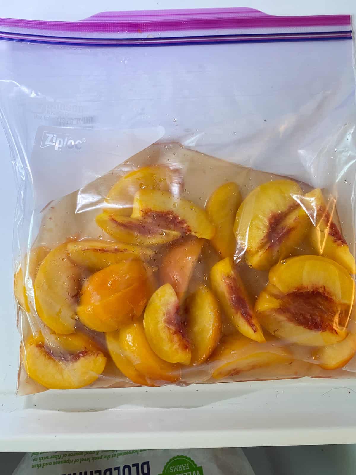 Sliced peaches in a zipper bag with liquid ingredients, ready to be frozen.