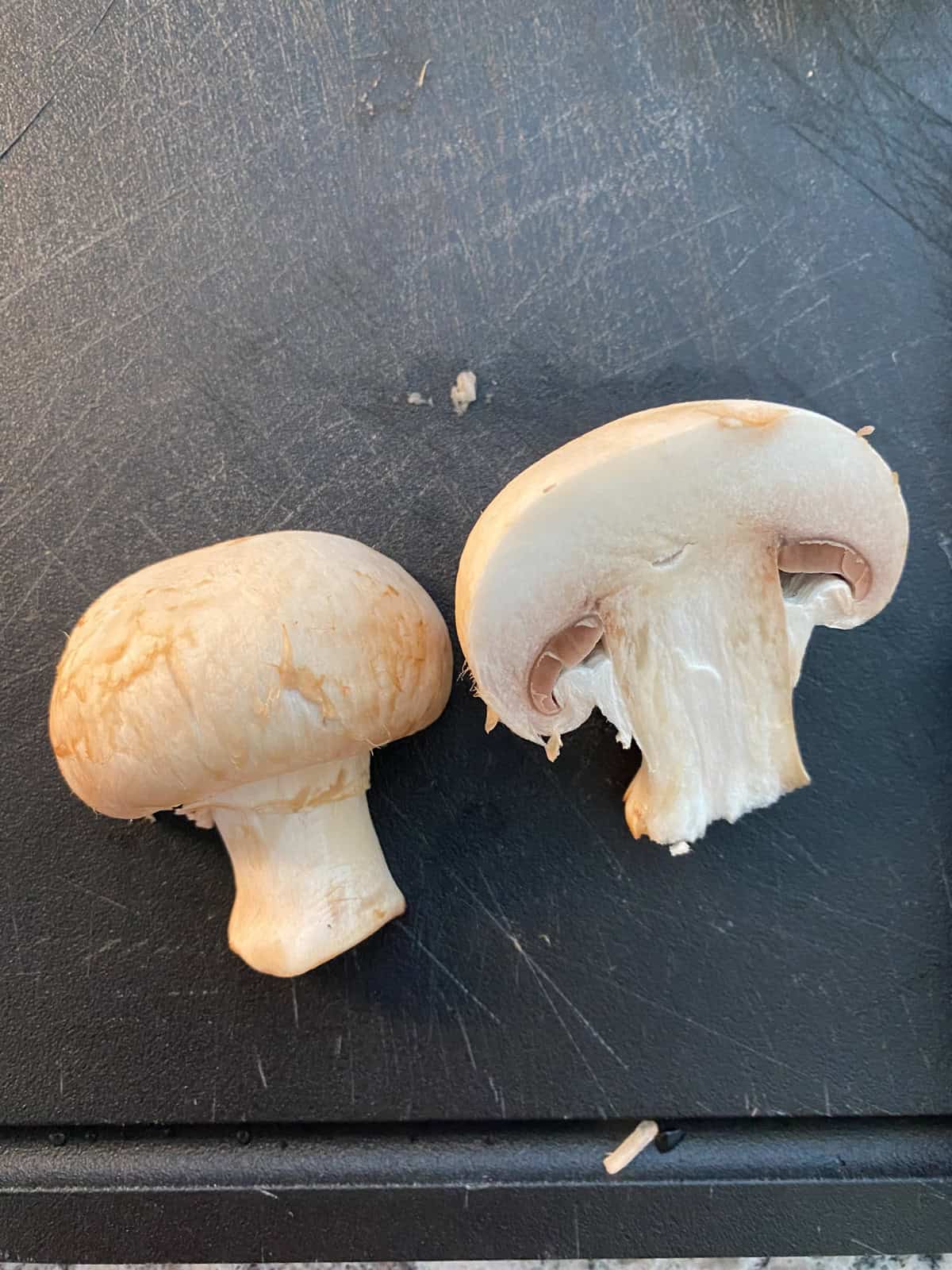 Mushroom cut in half on a cutting board.