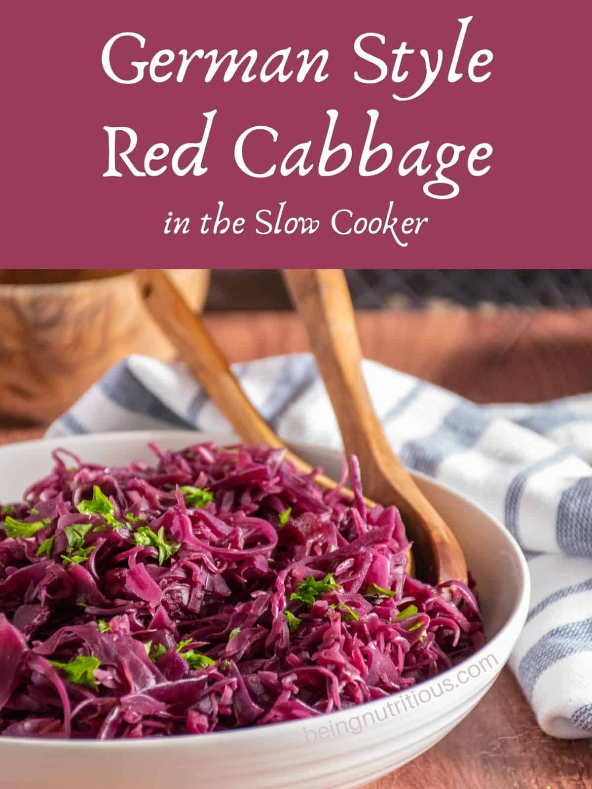 Bowl of cooked red cabbage with wooden spoons in the bowl. Text overlay: German Style Red Cabbage in the slow cooker.