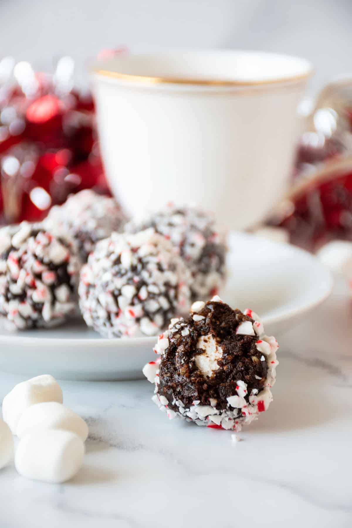 Small plate of peppermint hot cocoa bites, with a bite taken from one to reveal the marshmallow center.