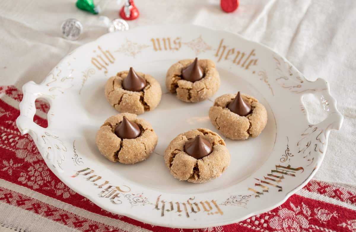 5 peanut butter cookies with chocolate kisses in them, on a serving plate.