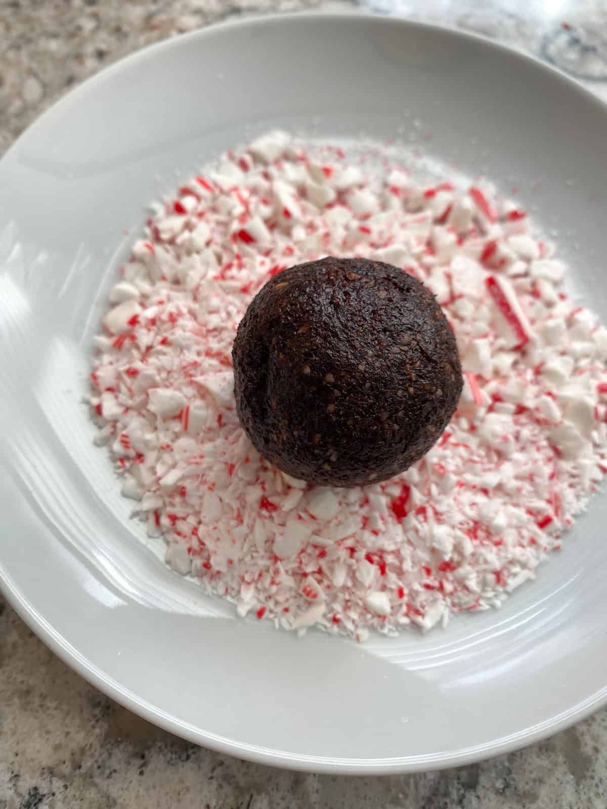 Formed cookie ball on a plate of crushed candy canes.