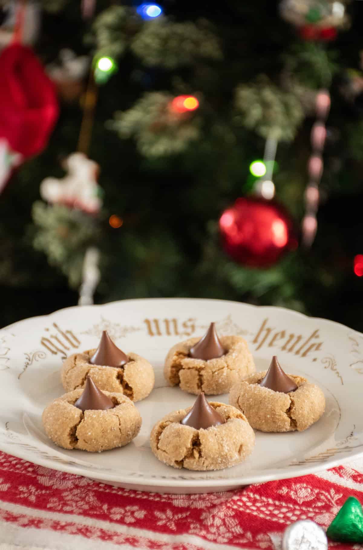 5 peanut butter cookies with chocolate kisses in them, on a serving plate.
