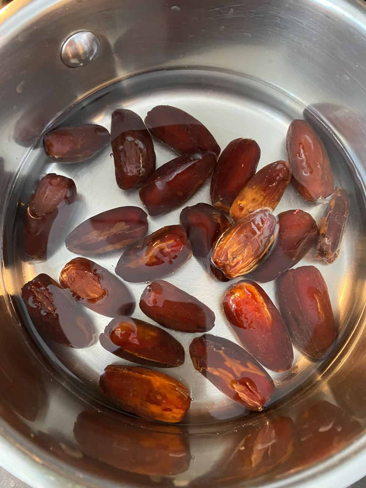 Whole, pitted dates in a saucepan of water.