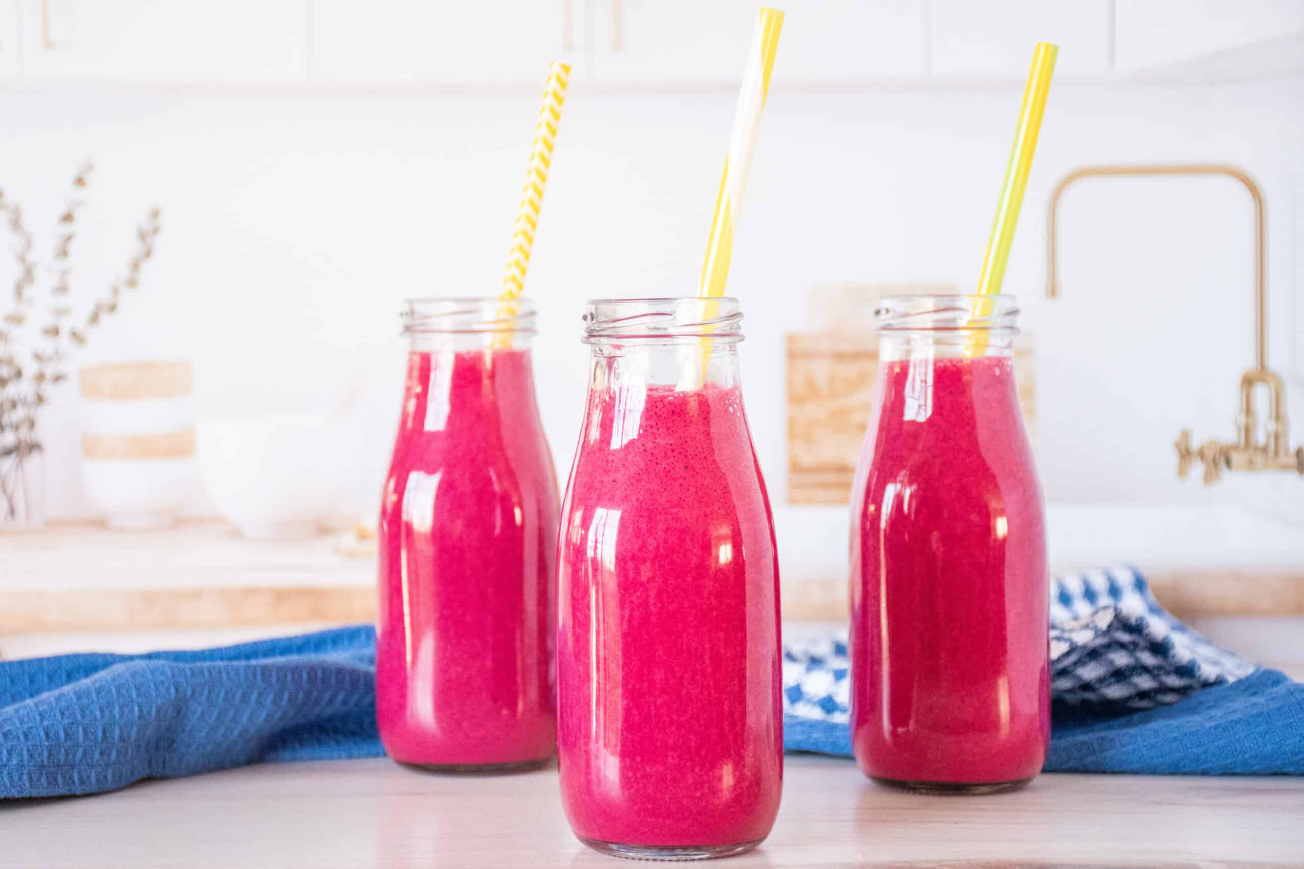 Three small jars of smoothie, with straws.