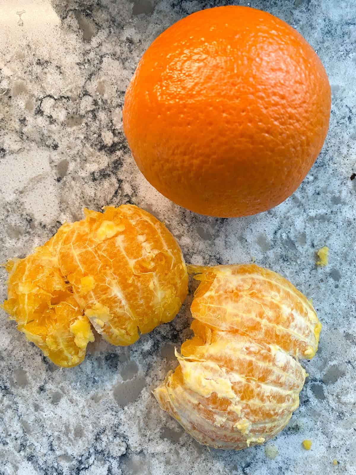 Pealed, halved orange, beside a whole orange.