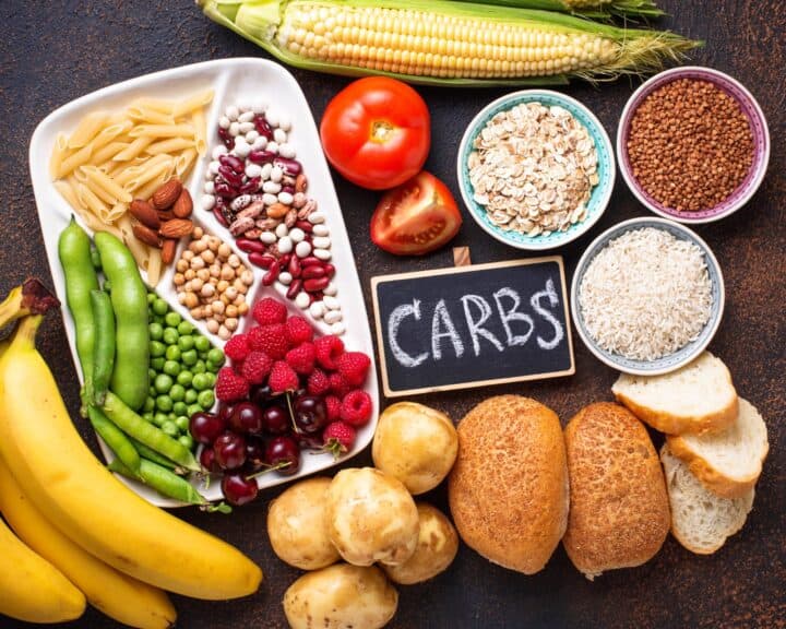 Various carbohydrate containing foods, with a chalkboard sign in the middle that says CARBS.