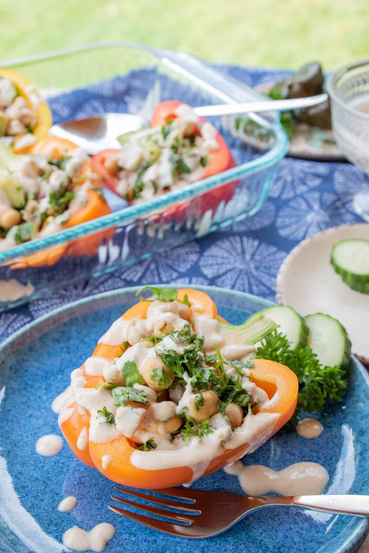 A blue plate with stuffed peppers and cucumber slices