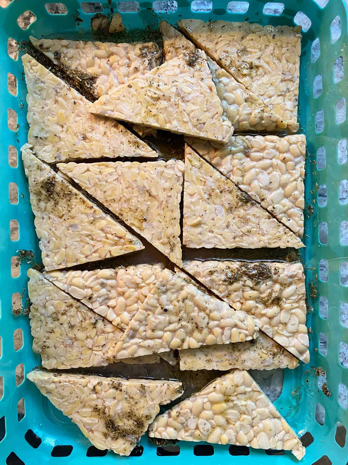 Sliced tempeh, marinating in a dish.