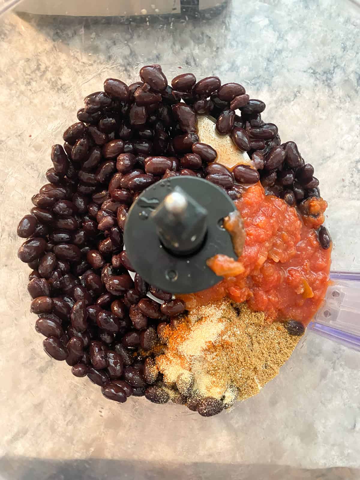 Whole ingredients for black bean dip in the food processor.