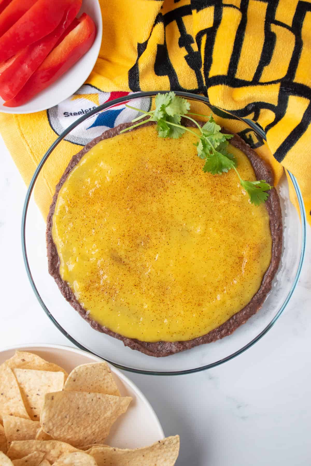 Dish with black bean dip and mango puree layered, garnished with fresh cilantro.