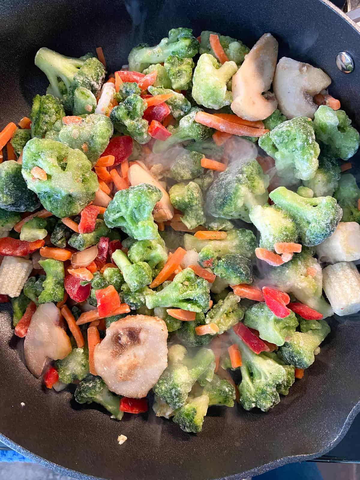 Frozen stir fry veggies in a hot pan.