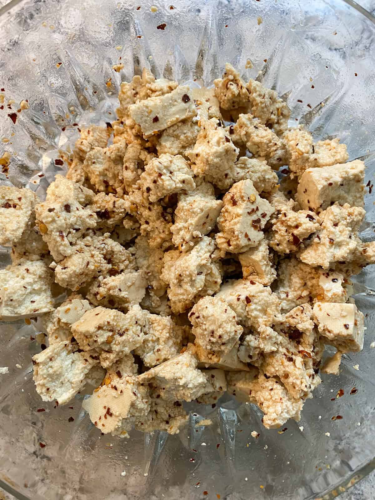 Torn tofu pieces tossed with marinade.