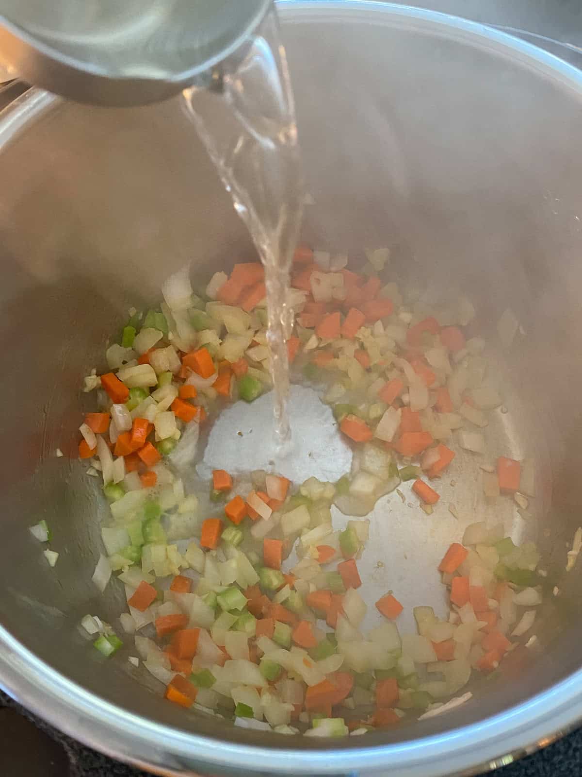 Wine being poured into the cooking vegetables.