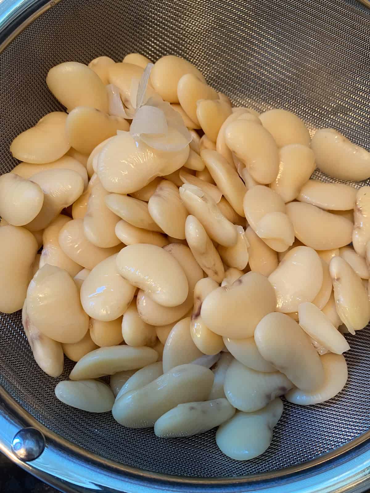 Soaked lima beans, drained in a strainer.