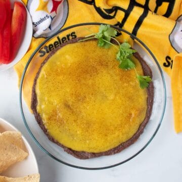 Dish with black bean dip and mango puree layered, garnished with fresh cilantro.