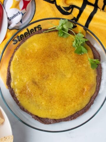 Dish with black bean dip and mango puree layered, garnished with fresh cilantro.
