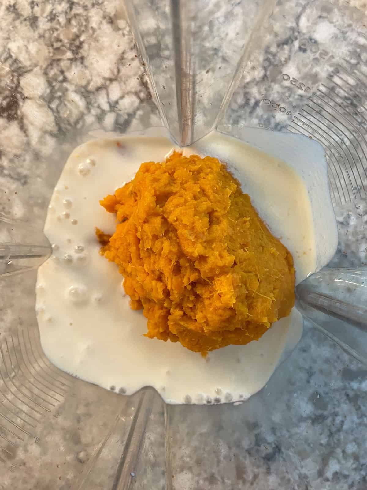 Milk and mashed sweet potato in a blender, ready to be blended.